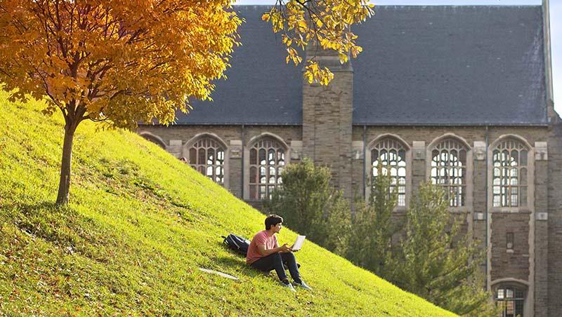 person sitting on hill with computer